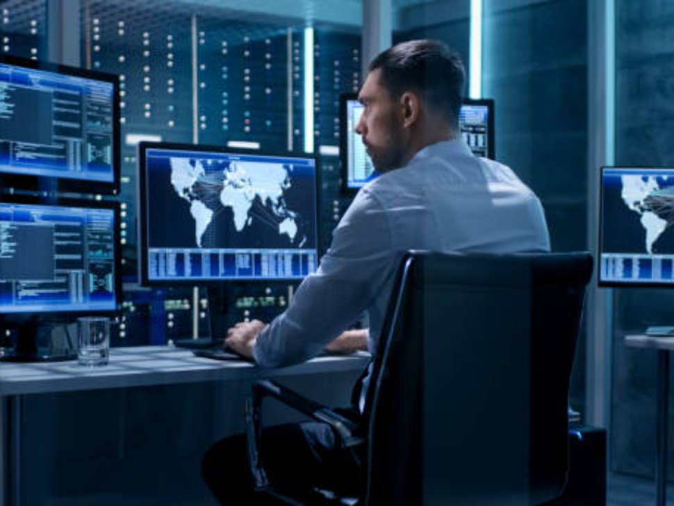Technical Controller Working at His Workstation with Multiple Displays. Displays Show Various Technical Information. He's Alone in System Control Center.